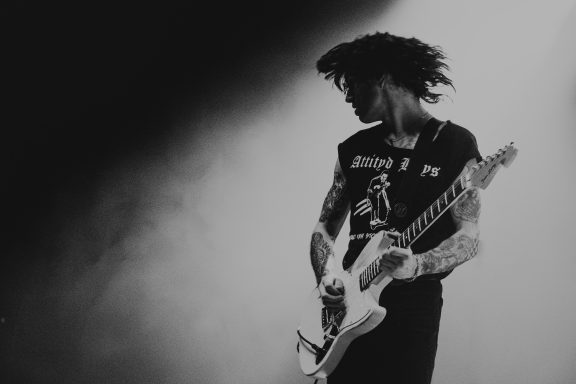 the guitarist Will Power from Bad Nerves in silhouette playing electric guitar on stage with dramatic lighting.