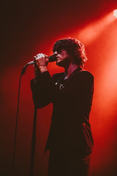 A singer performing on stage with dramatic lighting and a microphone.